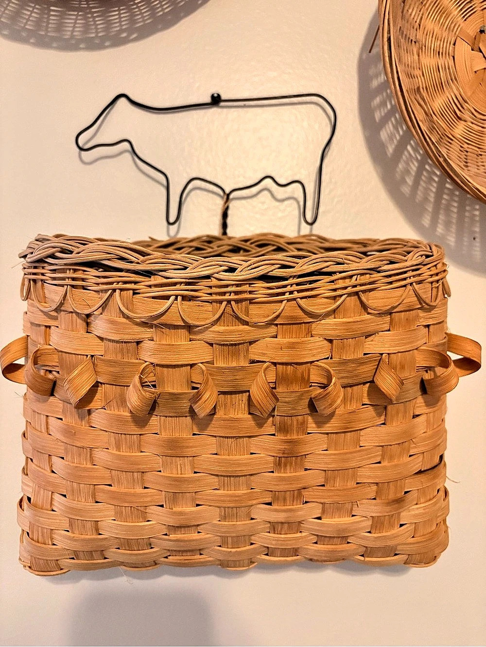 Hand Woven Wall Basket Tote with wire cow outline hanging.